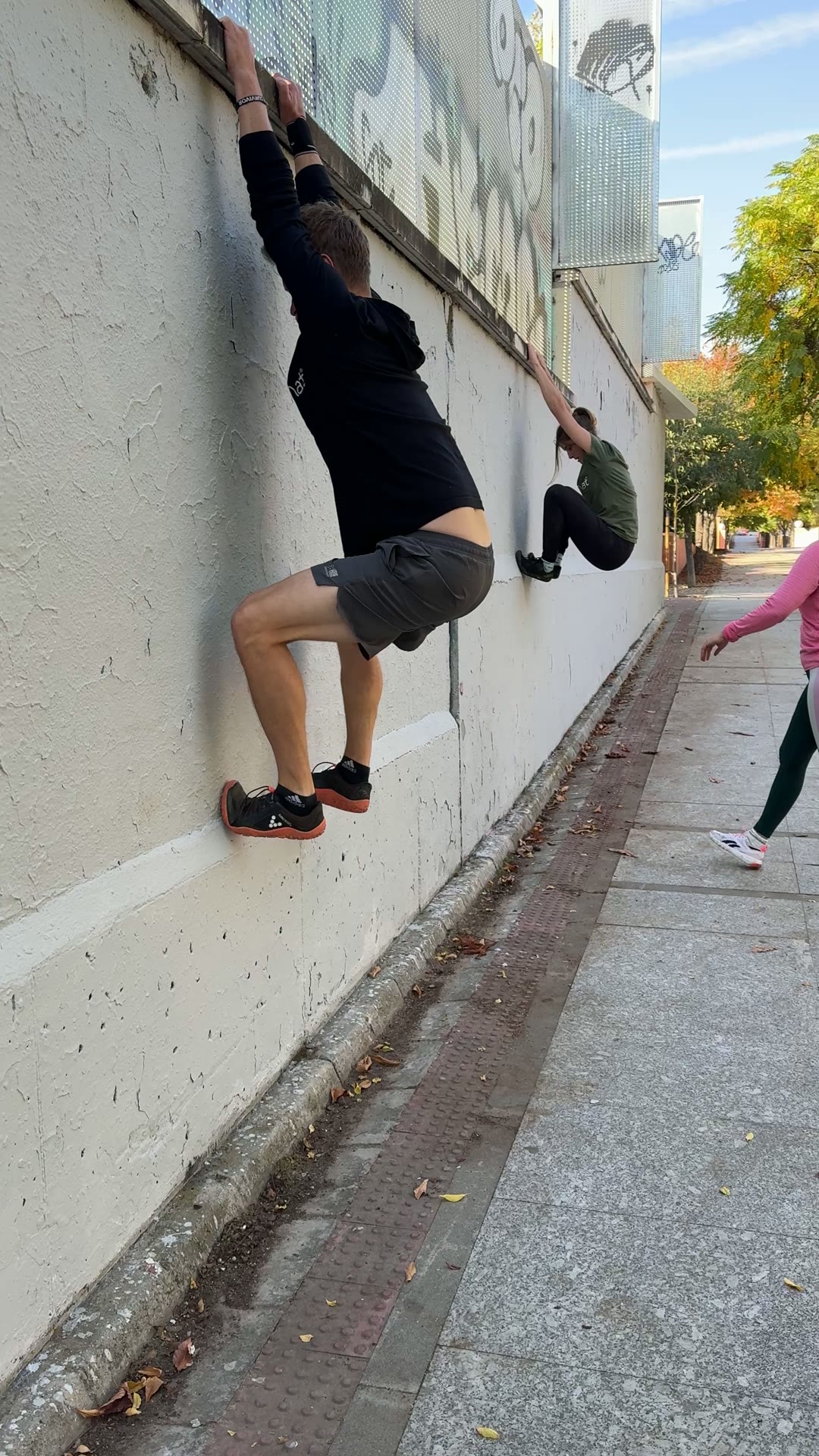 Alumno trepando por un muro en la calle durante la práctica exterior